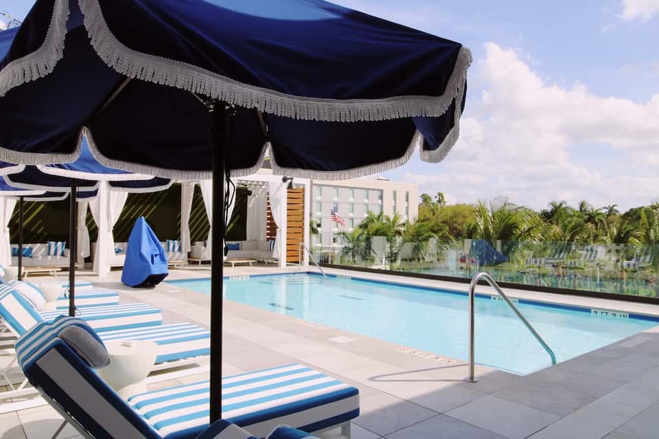 Outdoor pool deck with blue and white striped loungers under black fringe umbrellas