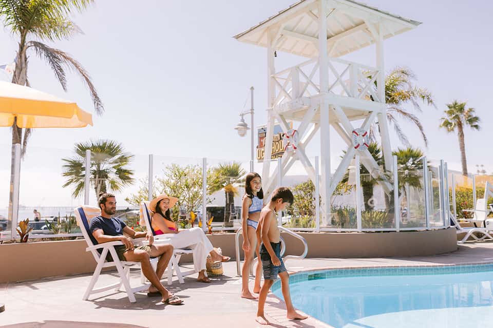 Family at resort pool with white observation tower and palm trees in background