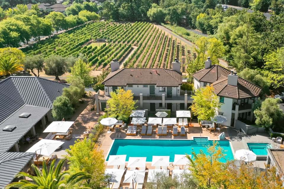 Aerial view of luxury resort with pool, vineyards, and spa facilities nestled in rolling hills