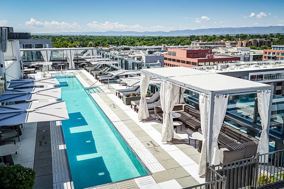 Modern rooftop pool deck with cabanas, lounge chairs, and mountain skyline views