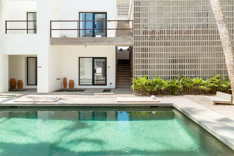 Modern poolside villa with white exterior, turquoise water, and minimalist architectural design