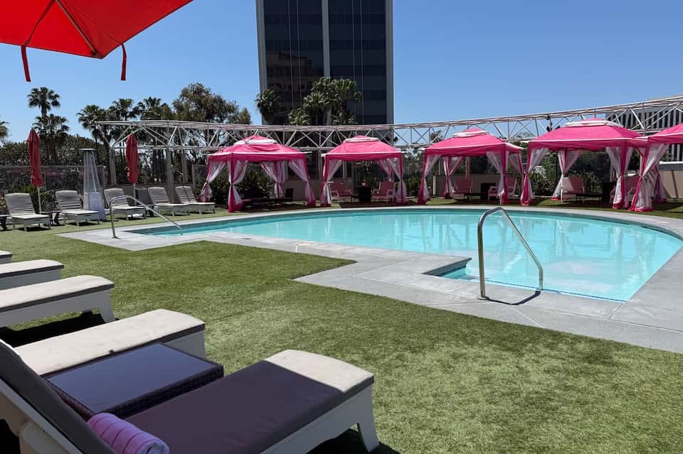 Resort pool with pink cabanas, umbrellas, and manicured lawn