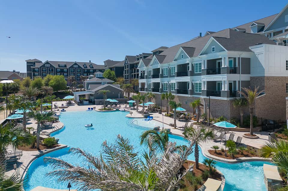 Aerial view of sprawling resort with multiple pools, colorful townhouses, and palm trees