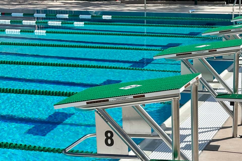 Olympic-style swimming pool with multiple lanes, lane dividers, and diving board platform