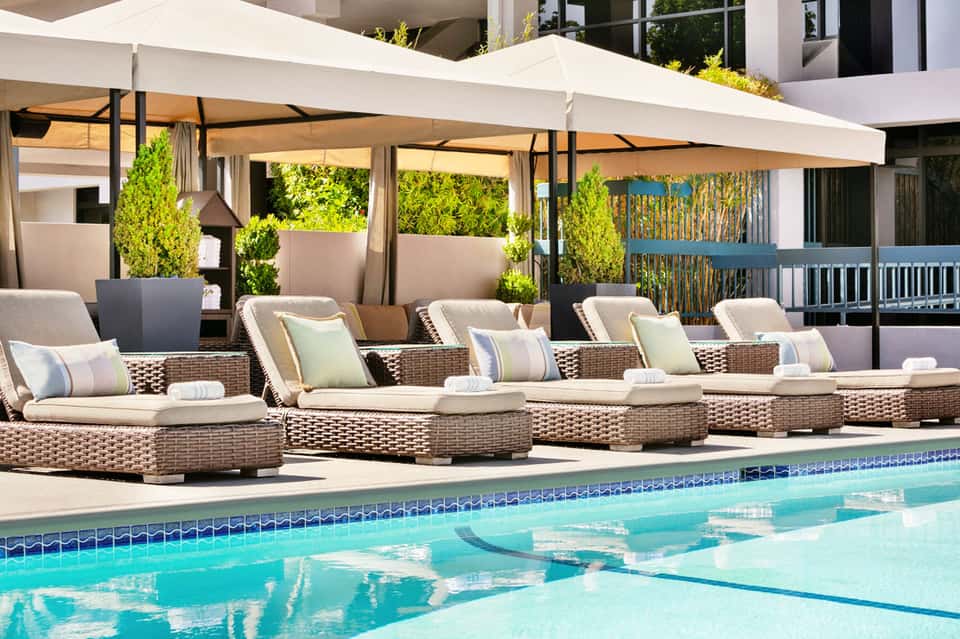Luxury pool deck with woven loungers, umbrellas, and lounge seating by resort swimming pool