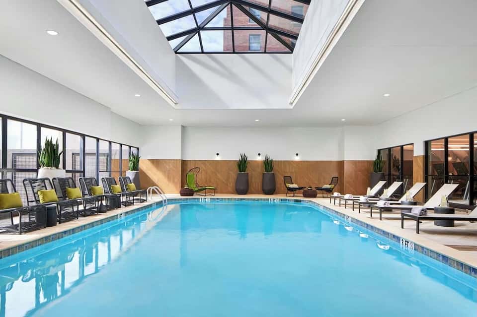 Indoor pool with skylights, wooden accents, lounging chairs with yellow cushions