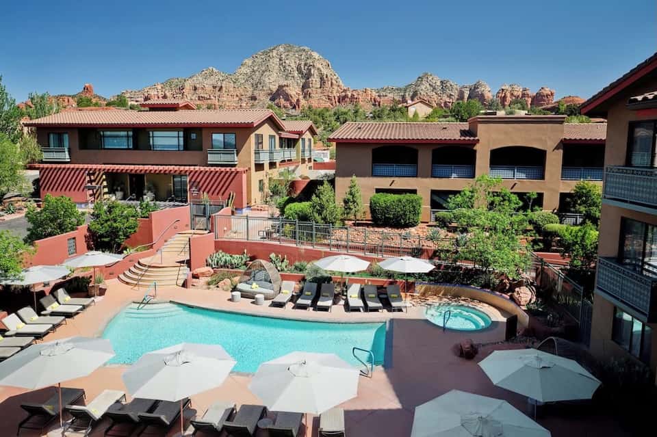 Resort pool and spa with red-roofed buildings and dramatic red rock formations behind