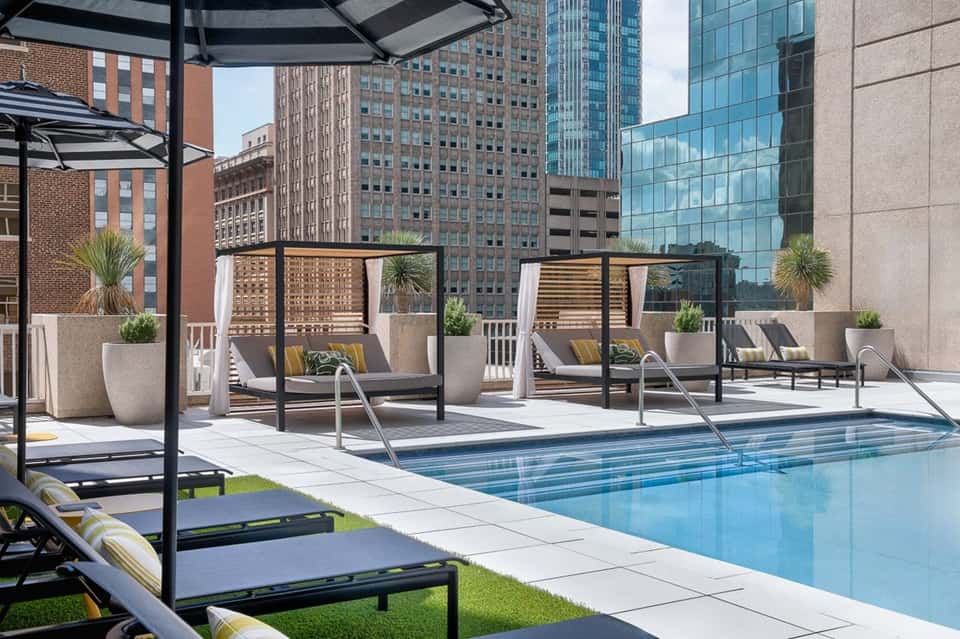 Modern rooftop pool overlooking downtown city skyline with lounge chairs and shade structures