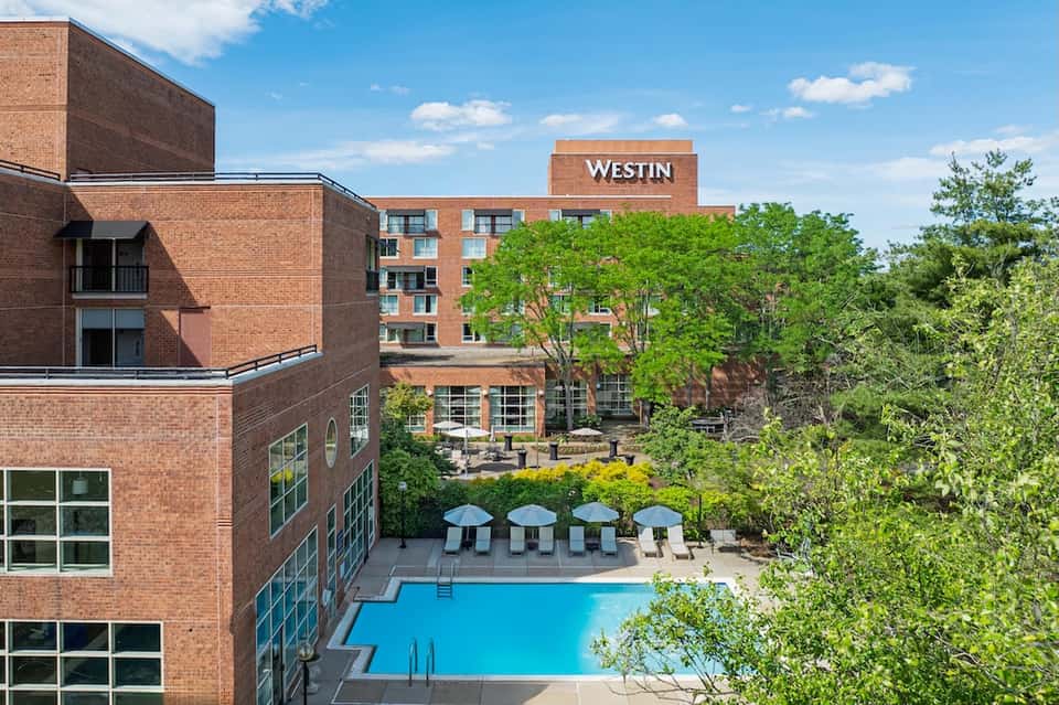 Westin Hotel with pool, umbrellas, courtyard seating area, and surrounding brick architecture