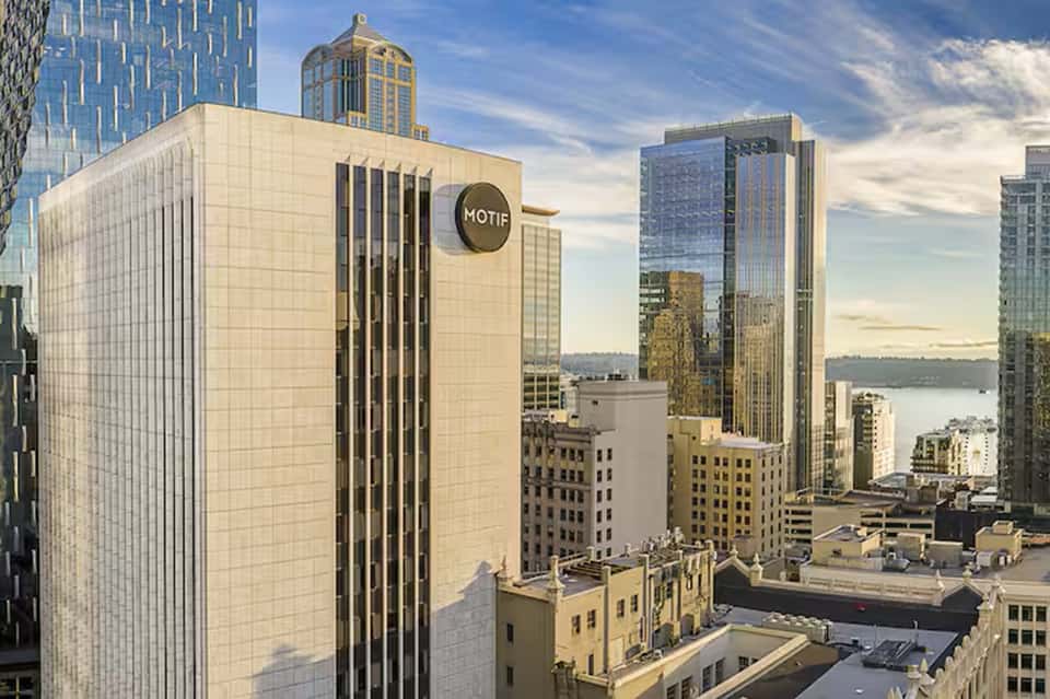 Urban hotel exterior with Motif branding, light-colored tile facade, and city skyline views