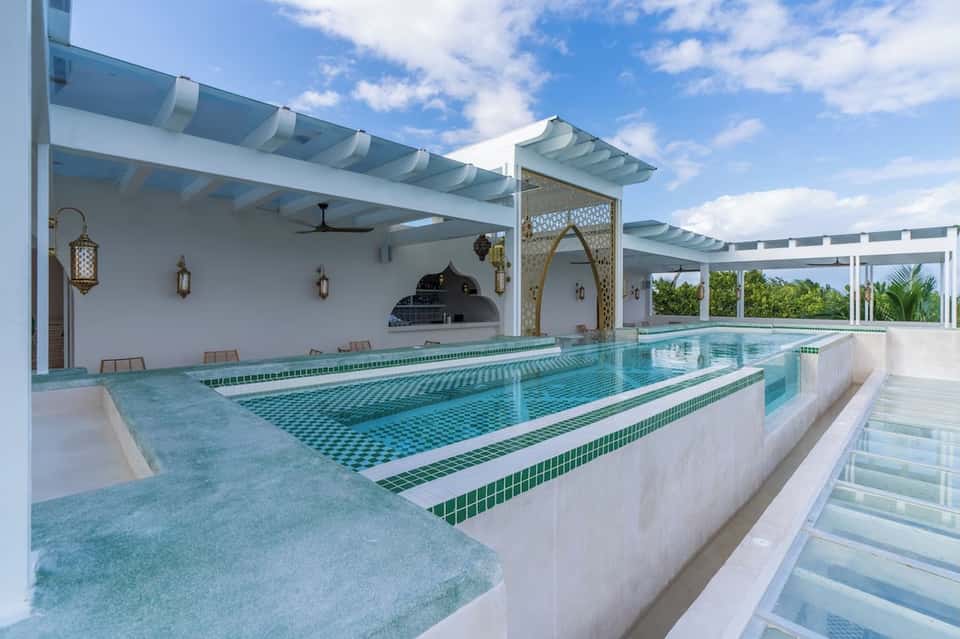 Indoor lap pool with Moroccan-style arches and white pergola ceiling