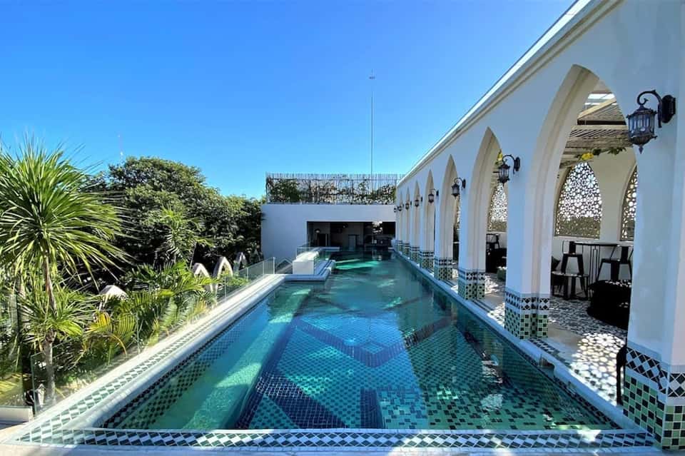 Elegant indoor lap pool with Moroccan-style white archways and decorative tile accents