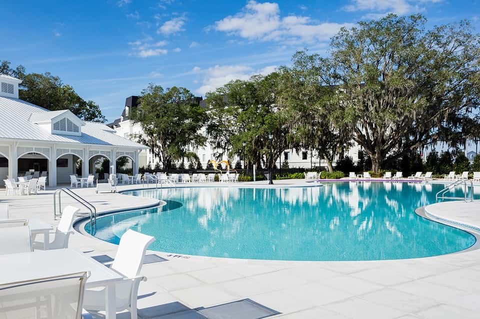 Large curved resort pool with white cabana, lounge chairs, oak trees, and manicured lawn