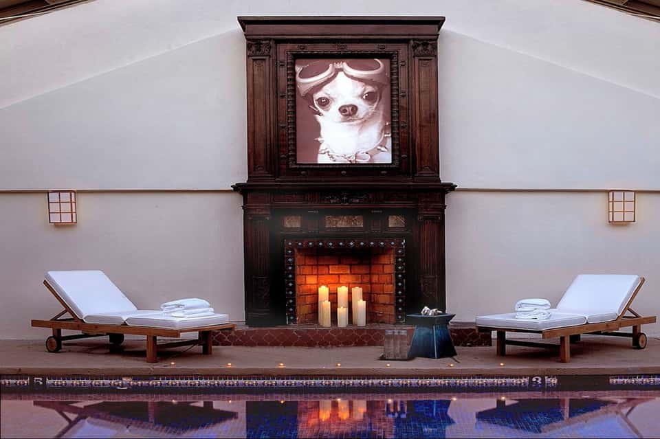 Luxury spa fireplace lounge with wooden loungers, white towels, ornate dark mantel, and lit candles