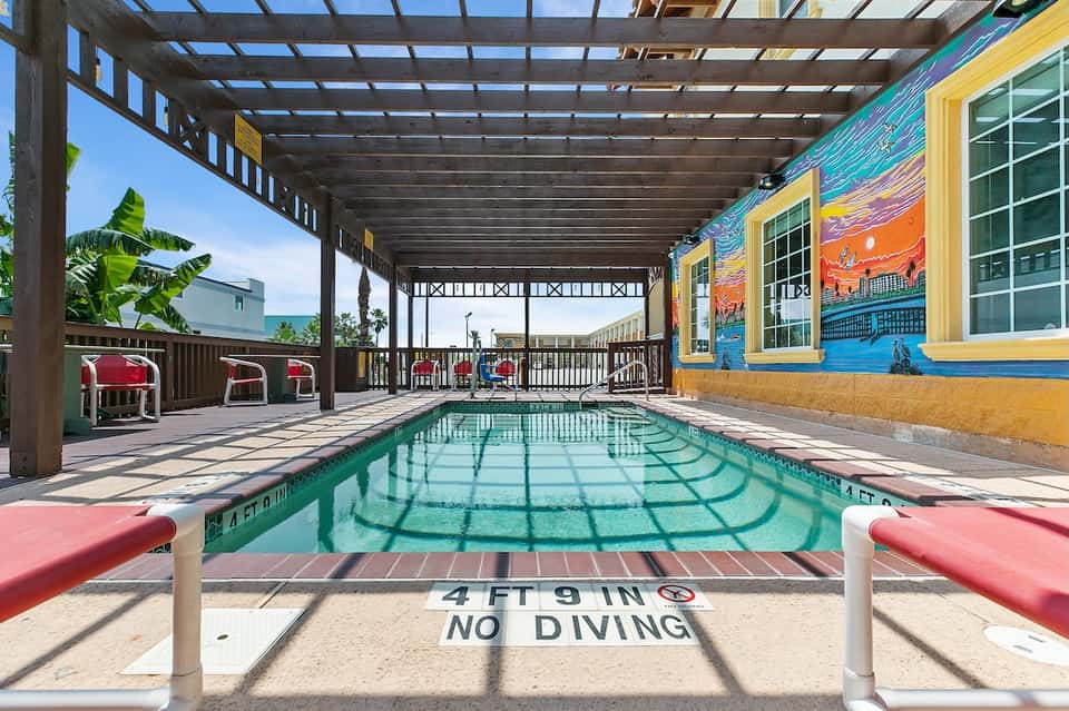 Indoor lap pool with yellow-framed murals, pergola ceiling, and colorful artwork