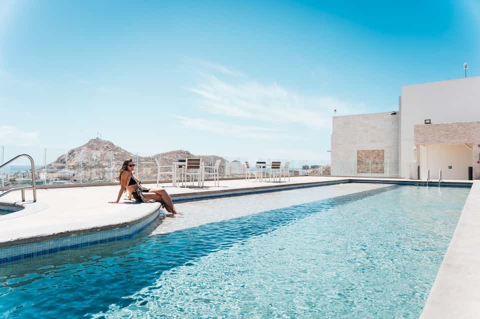 Modern rooftop infinity pool with desert mountain backdrop and minimalist white architecture