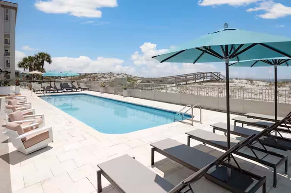Elevated pool deck with blue umbrellas, lounge chairs, and expansive valley views