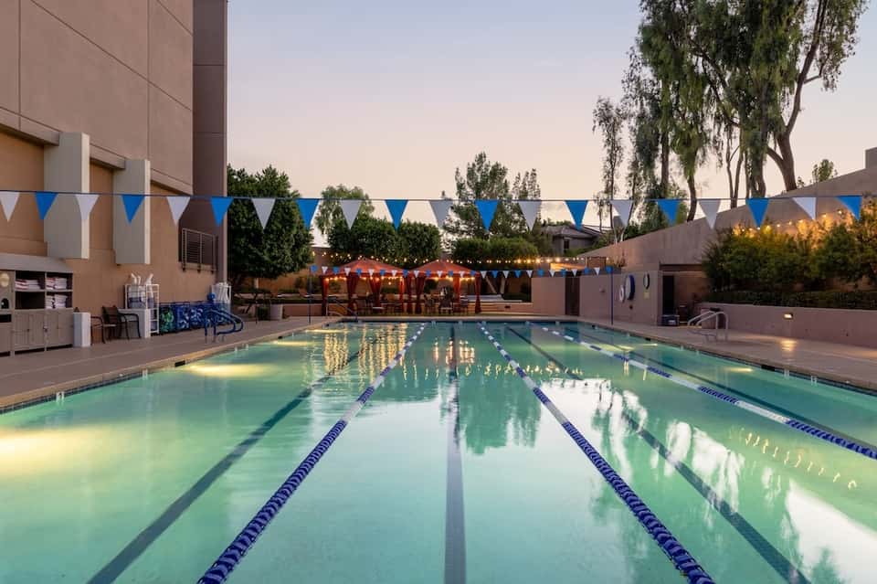 Illuminated lap pool with lane dividers and hotel building at twilight