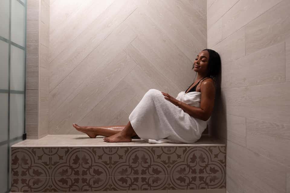 Woman relaxing in modern spa niche with white towel and decorative tile detailing on walls