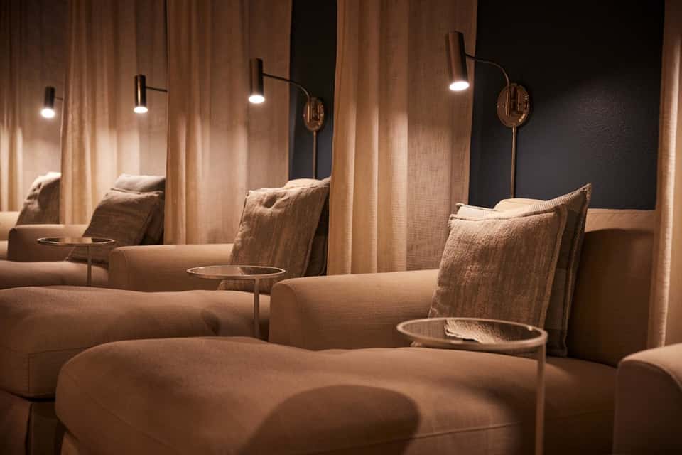 Luxury spa relaxation lounge with beige recliners, warm lighting, and curtained privacy spaces
