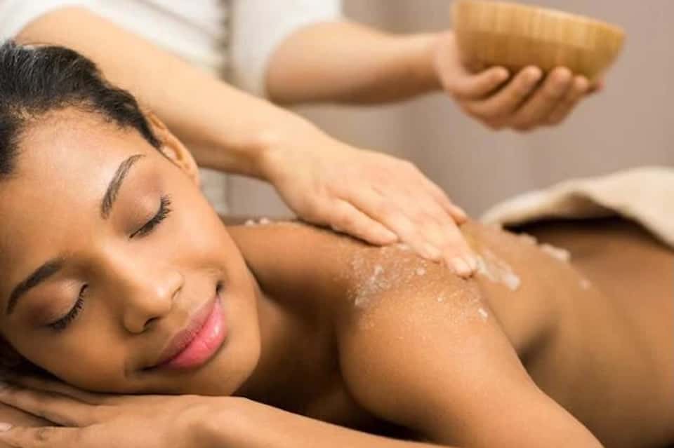 Woman receiving relaxing spa massage with exfoliation treatment on shoulders and back