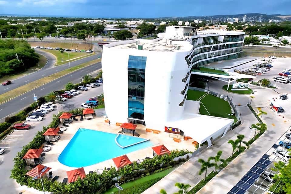 Aerial view of modern waterfront resort with turquoise pool and curved white building