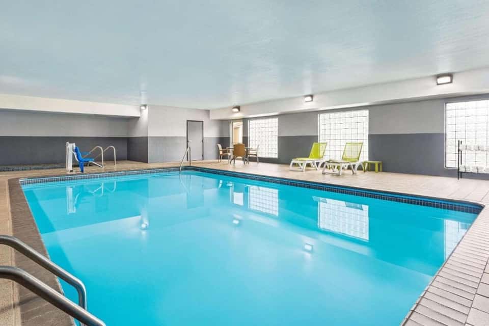 Indoor lap pool with bright blue water, windows, and lounge seating in contemporary facility