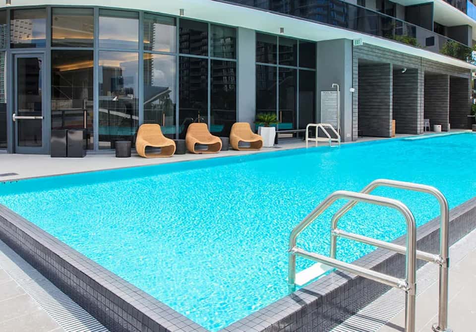 Modern rooftop pool with crystalline water, contemporary loungers, and urban building backdrop