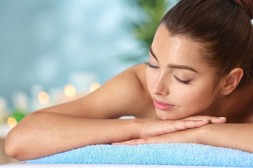 Woman relaxing poolside resting her head on folded arms on blue towel