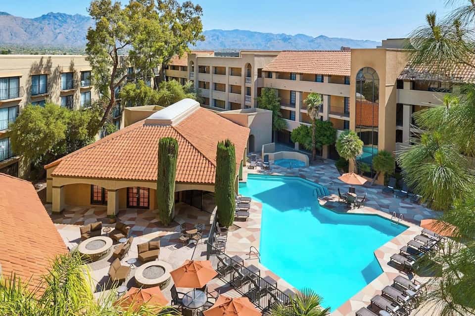 Aerial view of resort pool complex with cabanas, fire pits, and mountain views