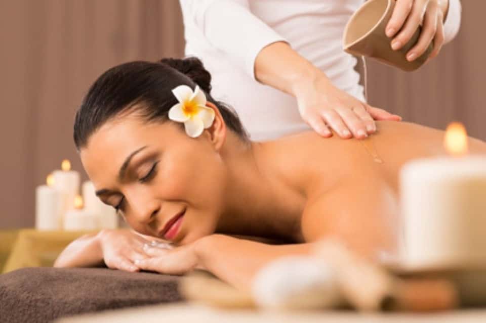 Spa massage treatment with relaxed woman receiving back massage in candlelit room