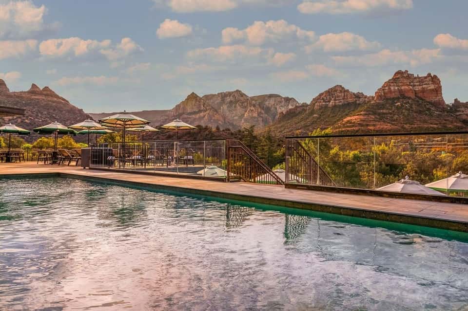 Infinity pool overlooking red rock formations and desert landscape with lounge seating and yellow umbrellas