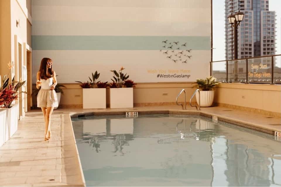 Indoor pool with geometric wall art, potted plants, and floor-to-ceiling windows