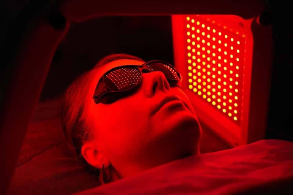 Red light therapy treatment with person wearing protective eyewear under LED light panel