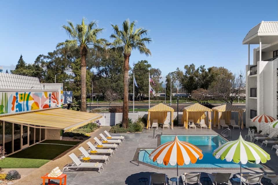 Resort pool area with colorful striped umbrellas, palm trees, and modern architecture