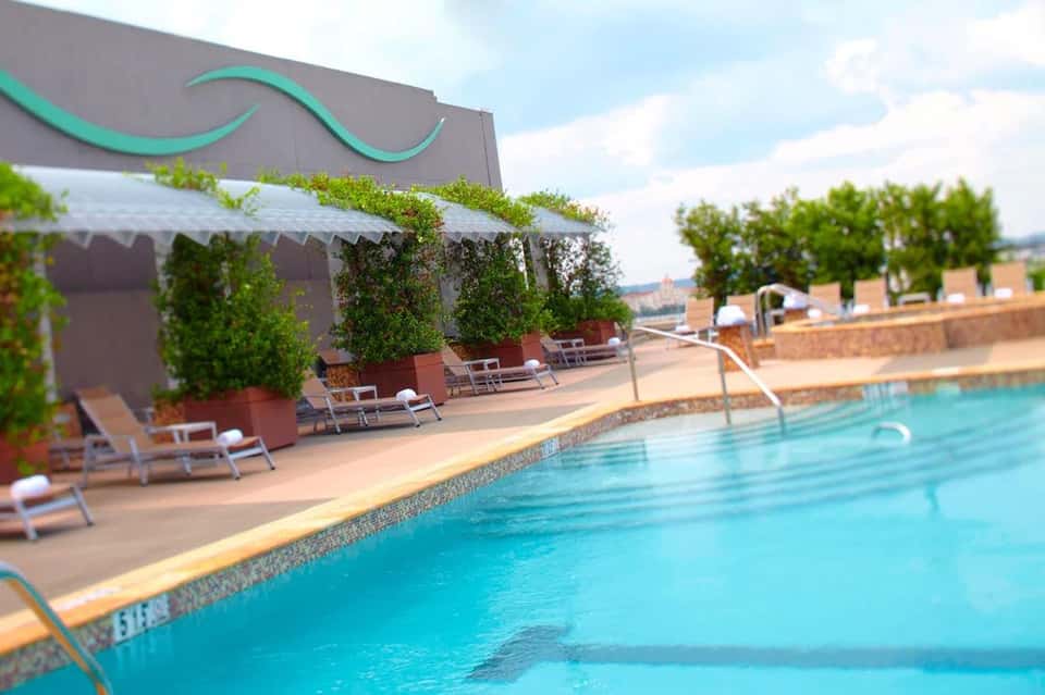 Resort swimming pool with lounge chairs, shade canopy, and scenic overlook of landscape