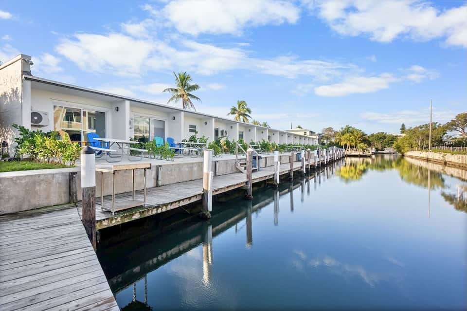 Row of modern waterfront cottages with docks along a calm canal with palm trees