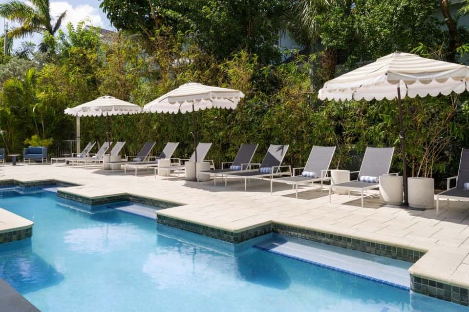 Luxury pool area with white umbrellas, loungers, and tropical landscaping at resort