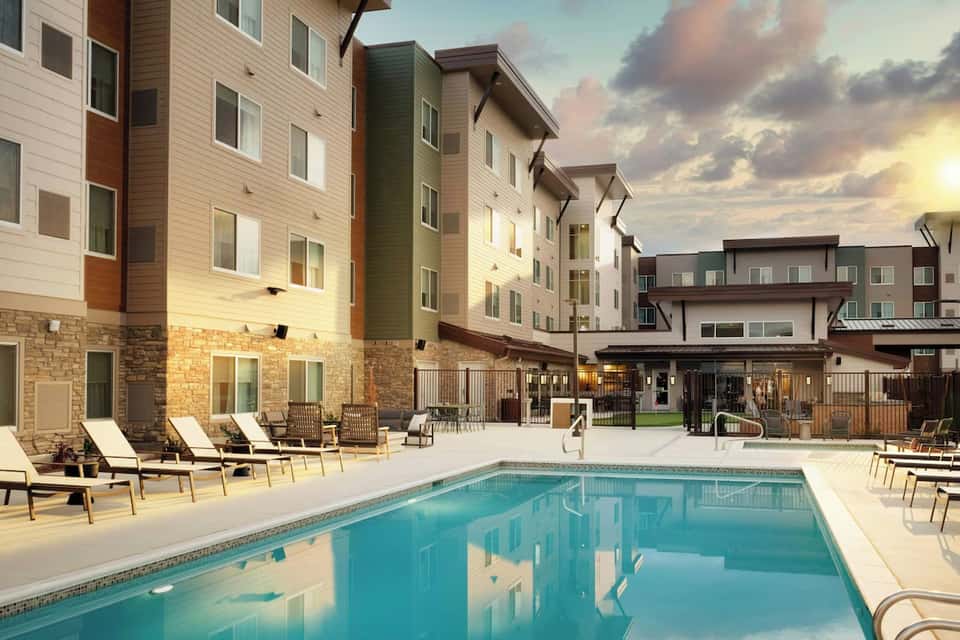Resort pool surrounded by multi-story residential buildings with stone and siding facades and landscaped grounds