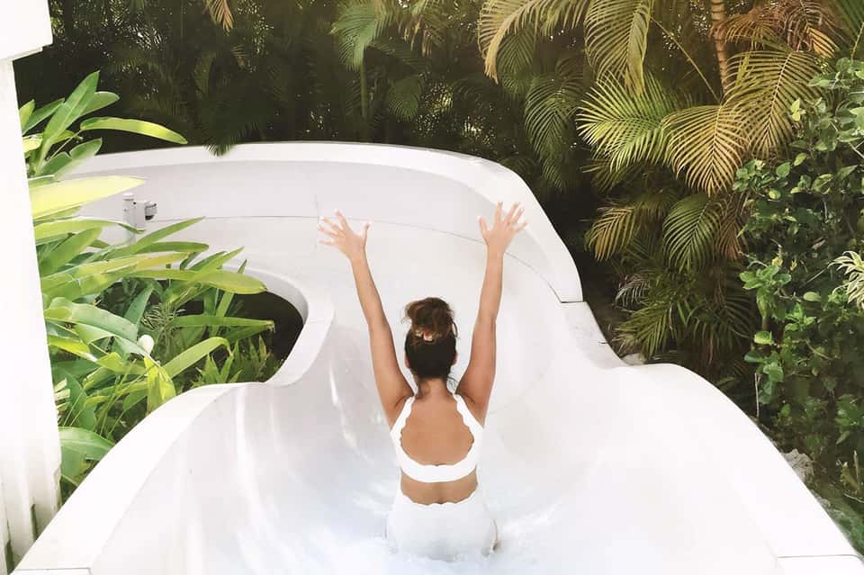 Woman on white water slide surrounded by tropical vegetation