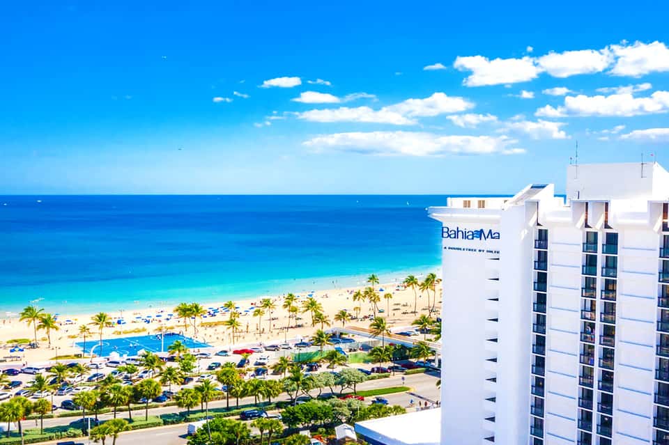 Bahia Mar beachfront hotel with white facade overlooking sandy beach, palm trees, and turquoise ocean