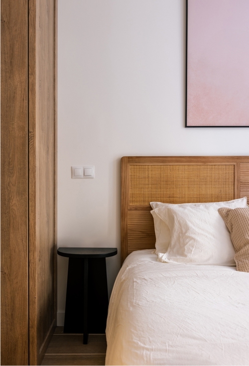 A cozy bedroom featuring a neatly made bed and a colorful painting hanging on the wall.