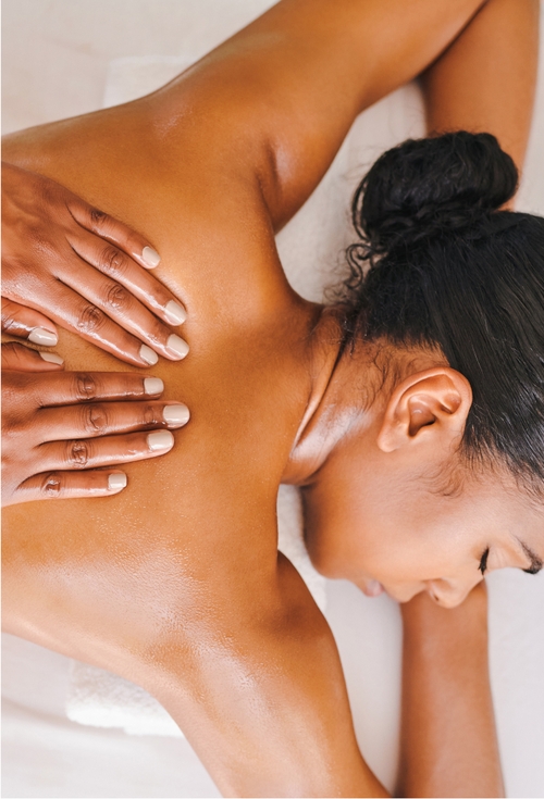 A woman enjoys a calming back massage, surrounded by a peaceful atmosphere.