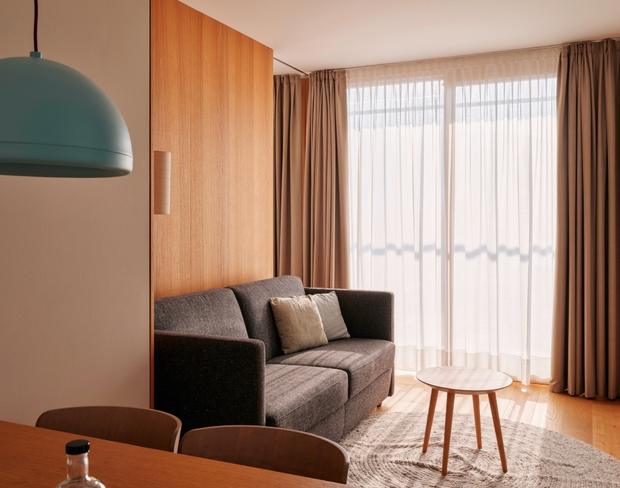 A chic modern living space with a plush couch, a sleek table, and a window that offers a view outside.