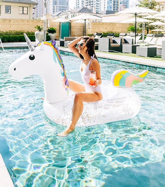 Woman drinking a beverage while floating on a unicorn floater in a hotel's pool