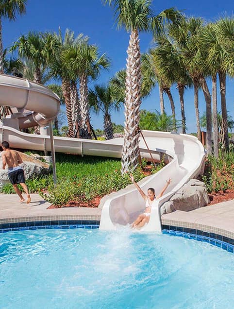 Child going down a water slide about to make a splash in a hotel pool
