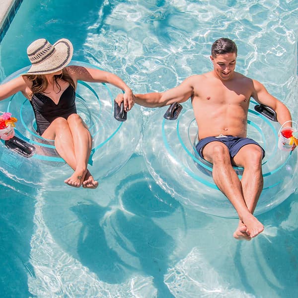 A couple floating in resort provided float tubes while drinking tropical drinks