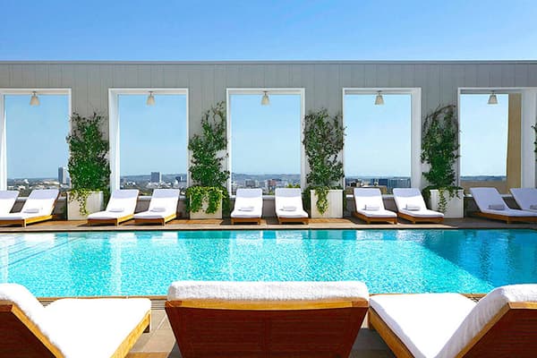 Hotel's rooftop pool lined with lounge chairs and view of city