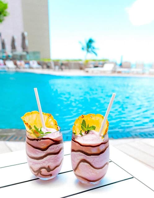 Tropical smoothies sitting on a table at a resort's pool deck