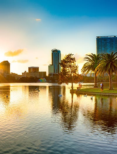 A popular park with a lake. High rise hotels and business buildings can be seen in the background of Orlando, FL